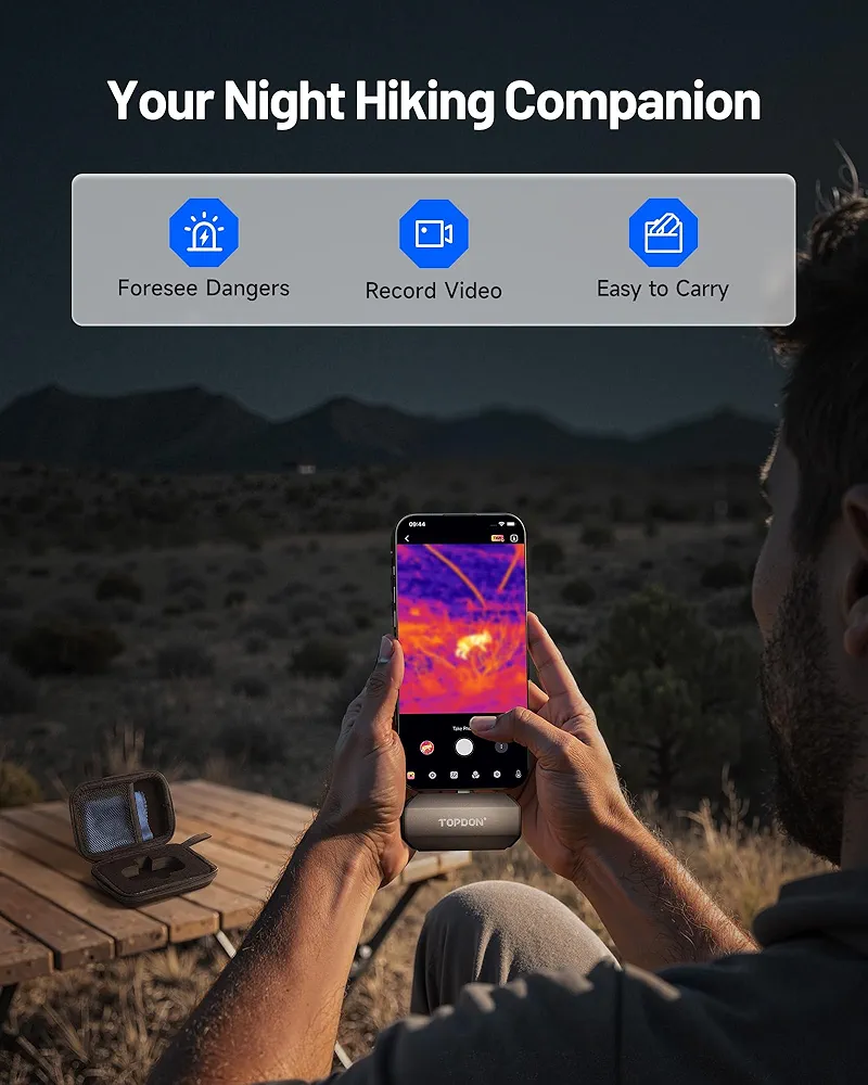 A thermal camera attachment for smartphones displayed on a phone screen showing a heat-mapped nighttime landscape view, positioned next to its compact carrying case on a wooden deck overlooking dark terrain. The image highlights three key features: danger detection capabilities, video recording function, and portable design.