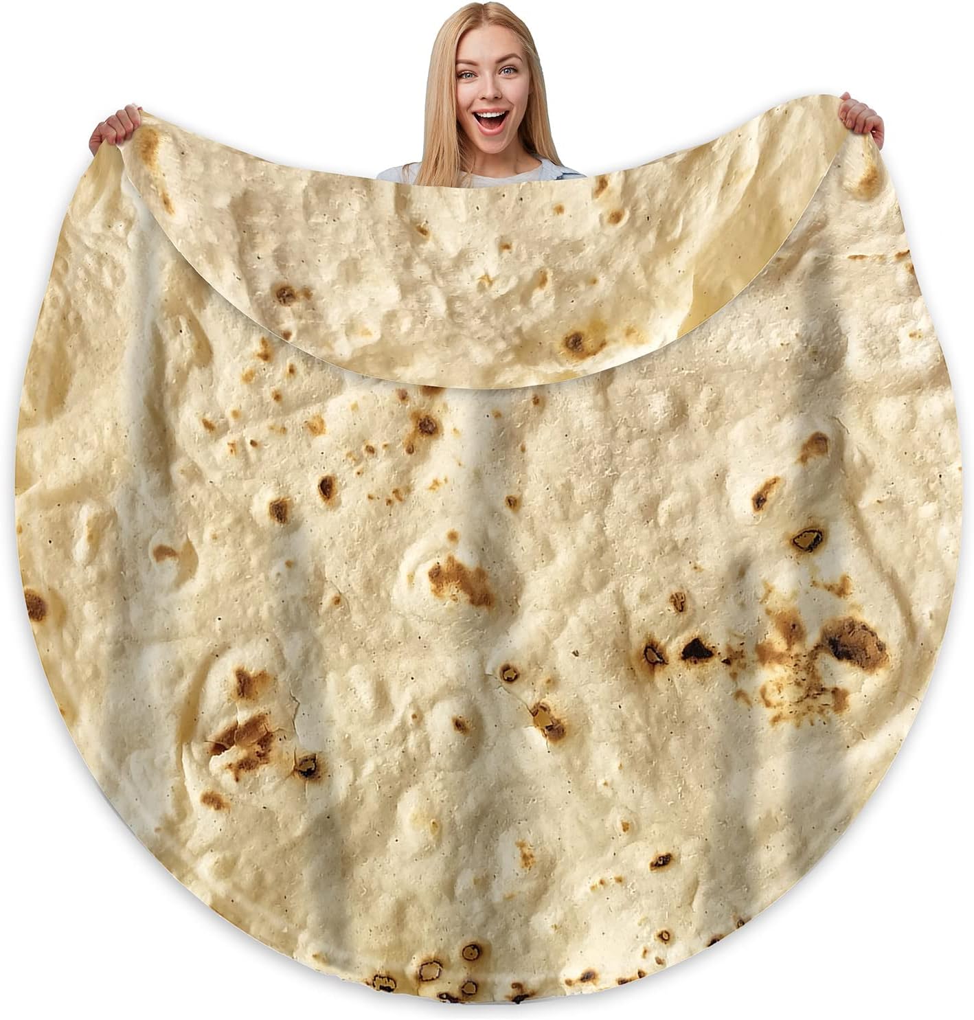 A large, circular blanket designed to resemble an oversized flour tortilla, complete with realistic charred spots and speckled texture. A smiling woman holds it open to display its full size and soft, plush fabric.