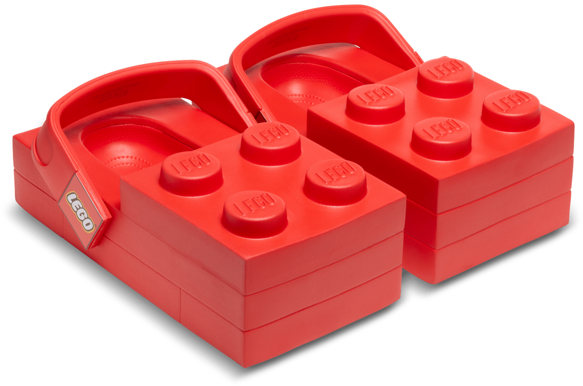 Red LEGO brick-shaped Crocs clogs featuring molded LEGO studs on top and adjustable heel straps, designed as a playful collaboration between LEGO and Crocs footwear brands.